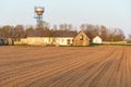 The building of a livestock farm, a water tower and a plowed field during sunset. An agricultural field on the territory of an Royalty Free Stock Photo