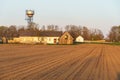 The building of a livestock farm, a water tower and a plowed field during sunset. An agricultural field on the territory of an Royalty Free Stock Photo