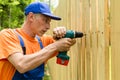Building master with machine constructs a wooden fence