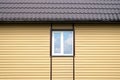 Building metal roof and wall finished with beige siding panels with white plastic window