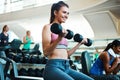 Building muscles with a smile on her face. an attractive young woman working out with dumbbells at the gym. Royalty Free Stock Photo