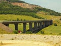 Building of new highway bridge. Concrete pillars above small valley, big hill with mine in background