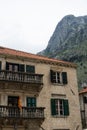building with orange clay tiles and the windows open and flag from Montenegro in Kotor. Big mountain with green trees and old Royalty Free Stock Photo