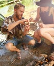 Building the perfect smore. a young couple making smores while camping.