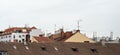 Building roofs with many tv and internet antennas, some satellite dishes, overcast sky above