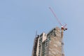 Building site with high-rise block under construction in an urban environment dominated by a large industrial crane Royalty Free Stock Photo