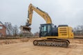 A building site there is a yellow excavator preparing the ground for foundations