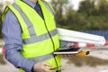 Building surveyor in hi vis carrying site plans and calculator