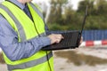 Building surveyor in hi vis vest entering data into his laptop