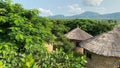 a building with a thatched roof surrounded by trees and hills Royalty Free Stock Photo