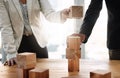 Building on their success together. two unrecognizable businesspeople stacking wooden blocks together in an office.