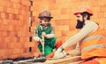 Building tools. A smiling builder in a hard hat buiding a brick wall. Worker installing red brick for construction site