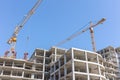 Building tower cranes near apartment building under construction against blue sky background Royalty Free Stock Photo