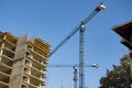 A building under construction and a construction crane against a blue sky on a bright sunny day. Royalty Free Stock Photo