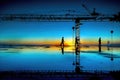 A building under construction at dawn in blue tones with workers and a crane backlit and the wet floor shows the reflections Royalty Free Stock Photo