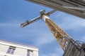 Building under construction and orange crane among city walls