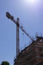 building under construction with scaffolding, yellow crane and blue sky