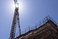 building under construction with scaffolding, yellow crane and blue sky