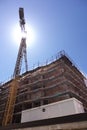 building under construction with scaffolding, yellow crane and blue sky