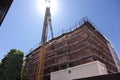 building under construction with scaffolding, yellow crane and blue sky