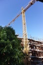 building under construction with scaffolding, yellow crane and blue sky