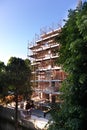 building under construction with scaffolding, yellow crane and blue sky