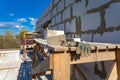 The building under construction, trowel with concrete and working glove on the foreground