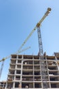 Building under construction with yellow building cranes against blue sky Royalty Free Stock Photo