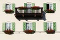 Building view with balcony and windows with green shutters decorated with flowers Royalty Free Stock Photo