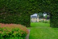 Building view through the opening in a long bush fence at the Royal Botanic Garden in Edinburgh, Scotland Royalty Free Stock Photo