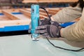 Building a wall for frame house. Worker use Laminate Trimmer for cutting drywall.