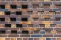 Building wall made of dark, yellow to brownish clinker bricks with various alternating patterns. The stones are offset in rows,