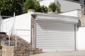 Building with white roller shutter garage door, stairs and gate outdoors Royalty Free Stock Photo