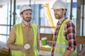 Building workers in yellow vests and helmets having coffee break Royalty Free Stock Photo