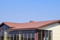 building with yellow walls and a red-brown roof. Modern materials of finish and roofing.