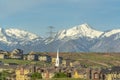 Buildings church and homes around golf course against snowy mountain and sky Royalty Free Stock Photo