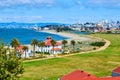 Buildings on edge of beach with people on trail and distant San Francisco skyscrapers and bridge Royalty Free Stock Photo