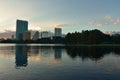 Buildings and forest reflected in lake in beautiful sunset at Eola Lake Park.