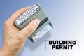 Buildings Permit about building activity and construction industry - concept with hand and plastic stamp with text Royalty Free Stock Photo