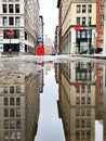 Buildings reflected in a puddle on Green Street in New York City