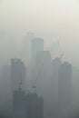 Buildings under construction with cranes in foggy sky