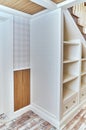 Built-in bookcase under a wooden staircase with white balusters