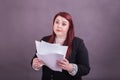 Youthful business woman holding stack of papers questioning look on her face