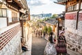 Bukchon Hanok village alley view with Asian tourists in Hanbok traditional dressing and dramatic light in Seoul South Korea