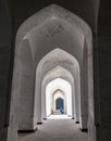 Bukhara, Uzbekistan, April 2018: Kalyan Mosque. A corridor of white arches, through which you can see a bench with a Muslim woman