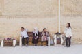 Bukhara, Uzbekistan - April 30, 2019. Uzbek people in traditional clothes near ancient brick wall