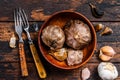 Bulbs and cloves of fermented black garlic in a plate. Dark wooden background. Top view Royalty Free Stock Photo