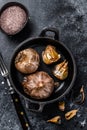 Bulbs of fermented black garlic in a pan. Black background. Top view Royalty Free Stock Photo