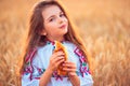 Bulgarian girl, beautiful woman, eating freshly baked banitsa, cheese pie during harvest In golden wheat field Royalty Free Stock Photo