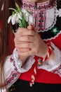 Bulgarian woman with bouquet spring snowdrop flowers and martenitsa March holiday Baba Marta, Bulgaria Royalty Free Stock Photo